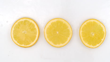 Drei-Frische-Zitronen,-Draufsicht-Auf-Fließendes-Wasser-Auf-Weißem-Hintergrund.